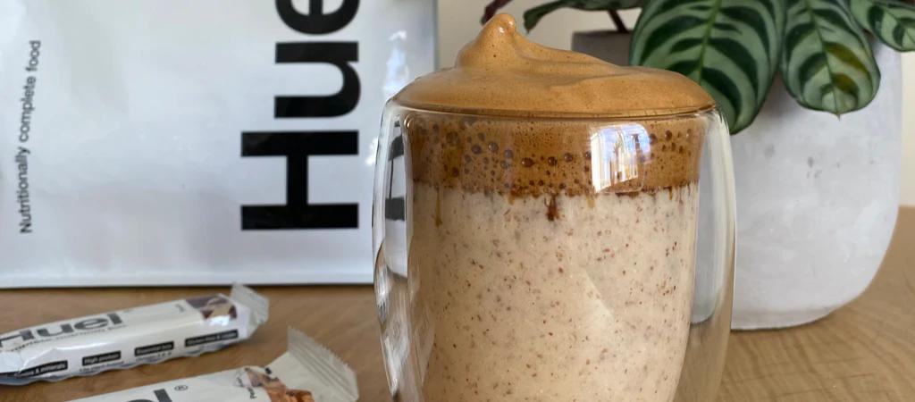 Huel Coffee in a clear glass with Huel Original Powder in the background