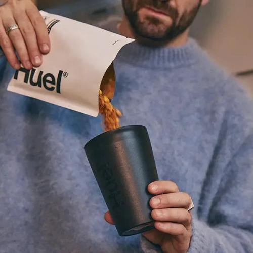 man pouring a Huel Hot & Savoury pack into a Huel Hot & Savoury pot