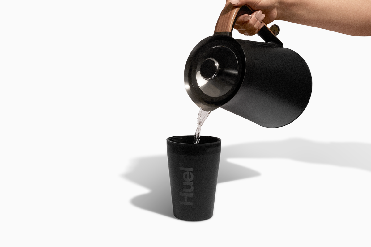 Image of someone pouring boiling water from a kettle into a black Huel pot