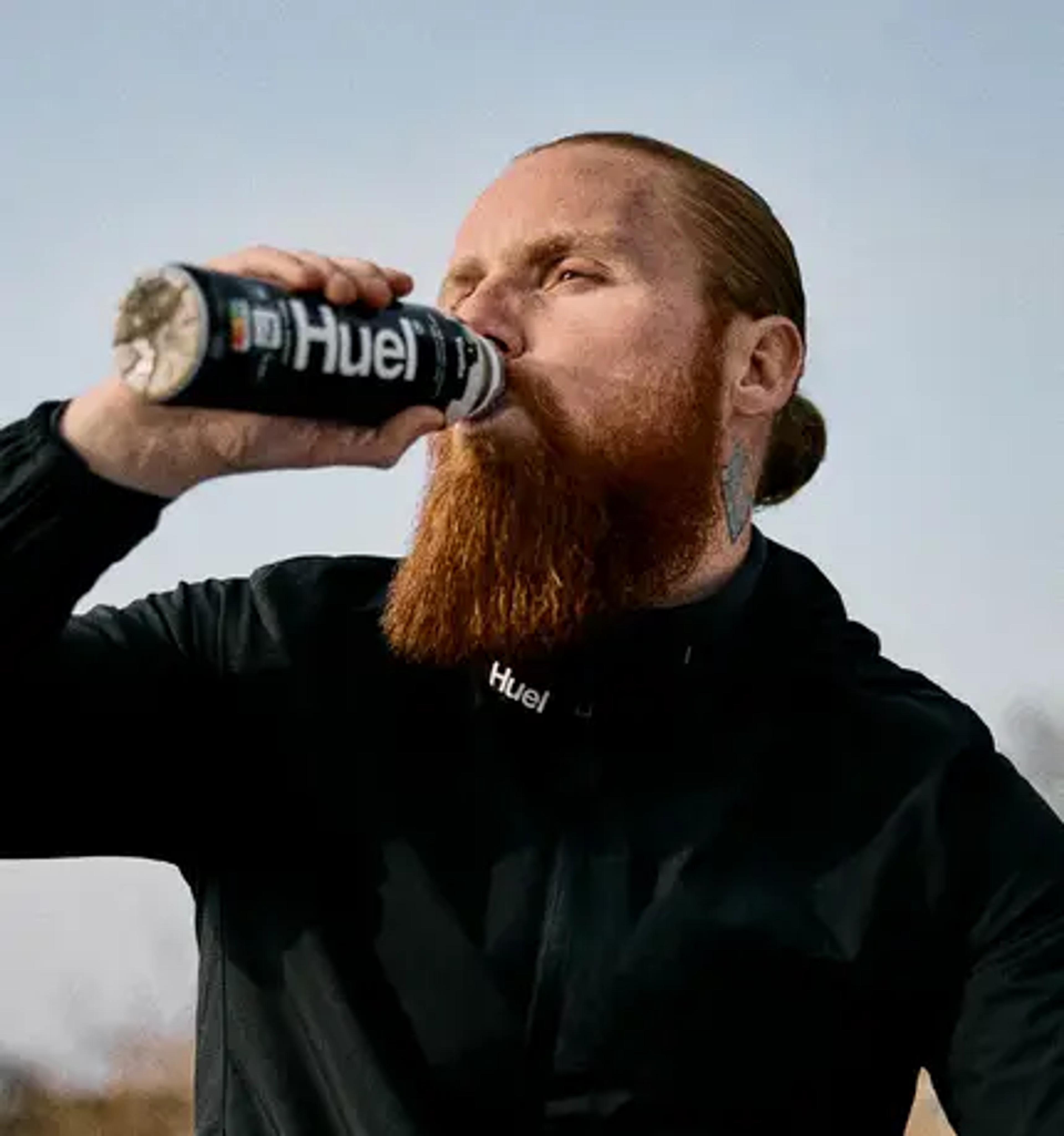 man walking out through a door holding a Huel Black Edition Ready-to-drink