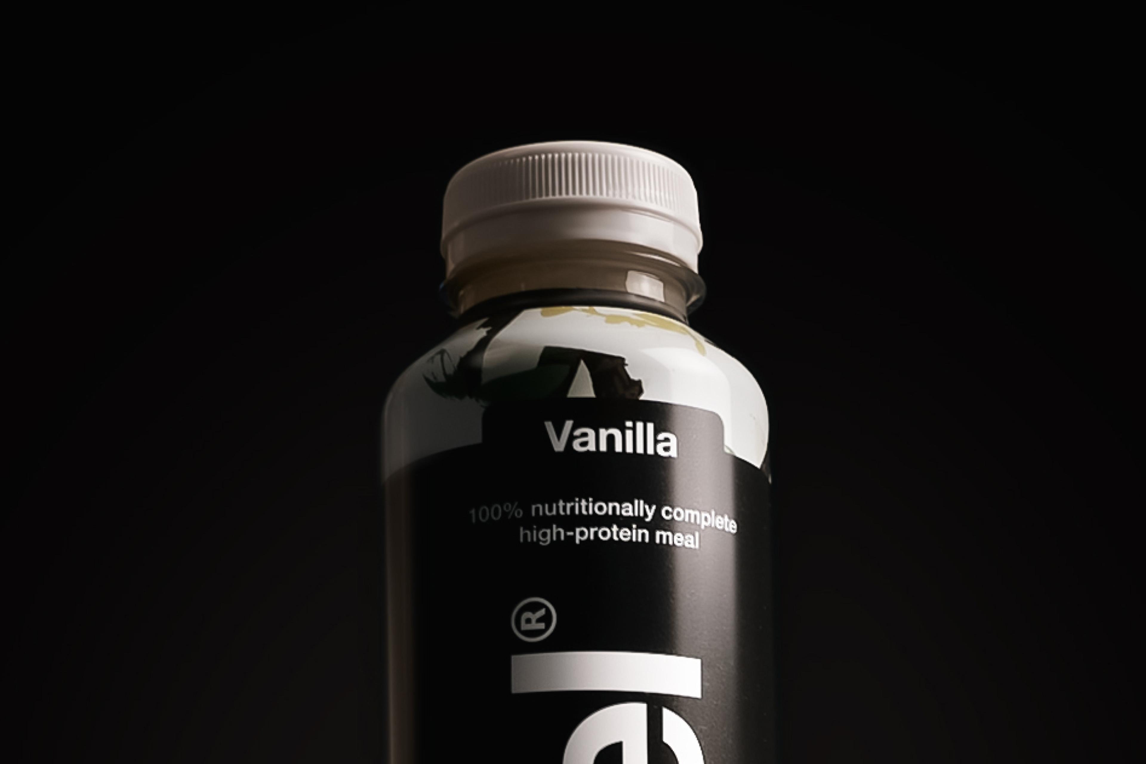 Top-down image of a glass of vanilla Huel Black Edition Ready-to-drink with ice, on a plain background
