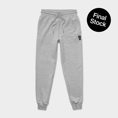 A flatlay image of grey huel joggers on a beige background