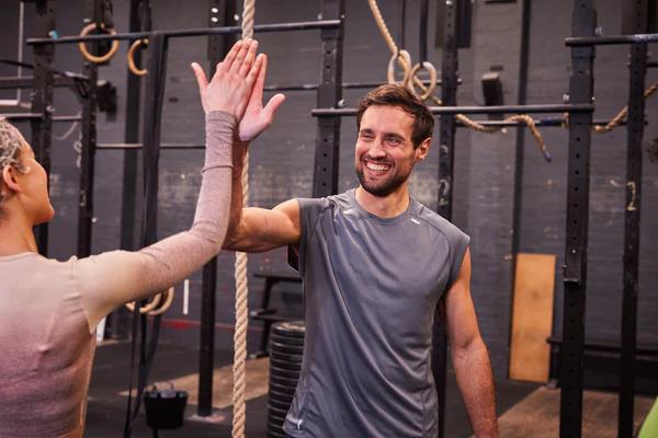 two people in a gym high fiving and smiling
