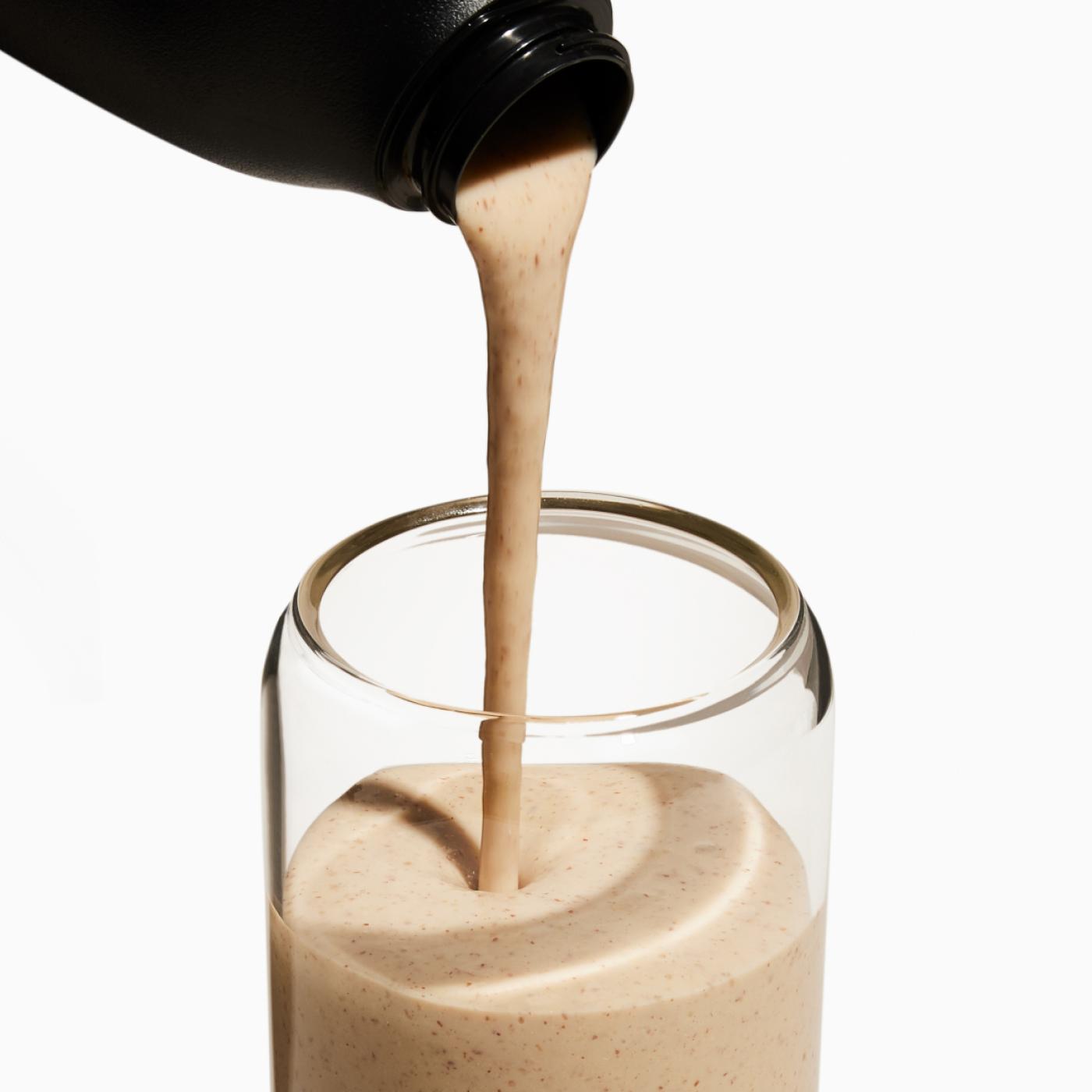 Shaker pouring Superblend into glass cup