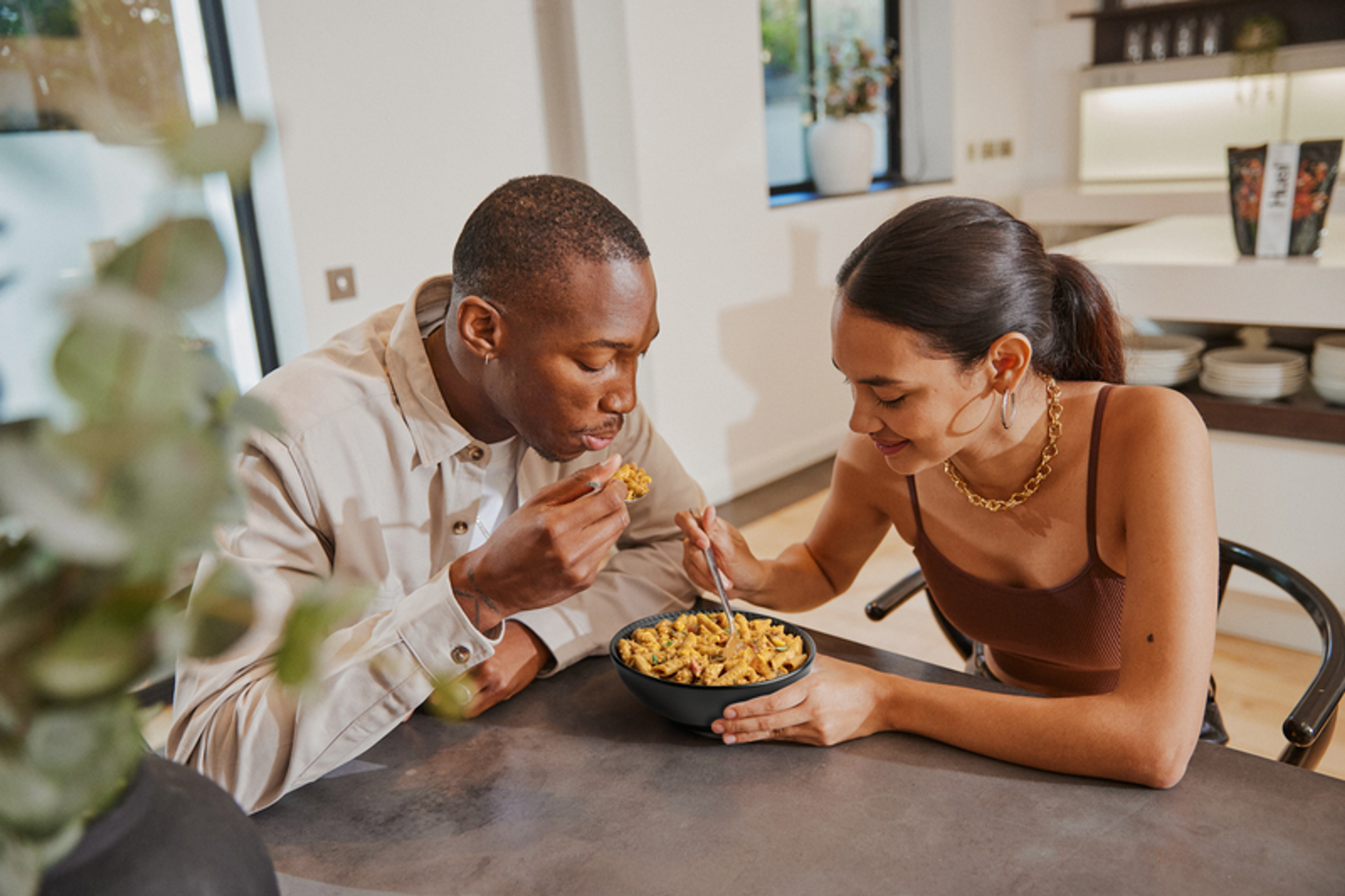 Man and woman eating a bowl of Huel Hot & Savoury Pasta