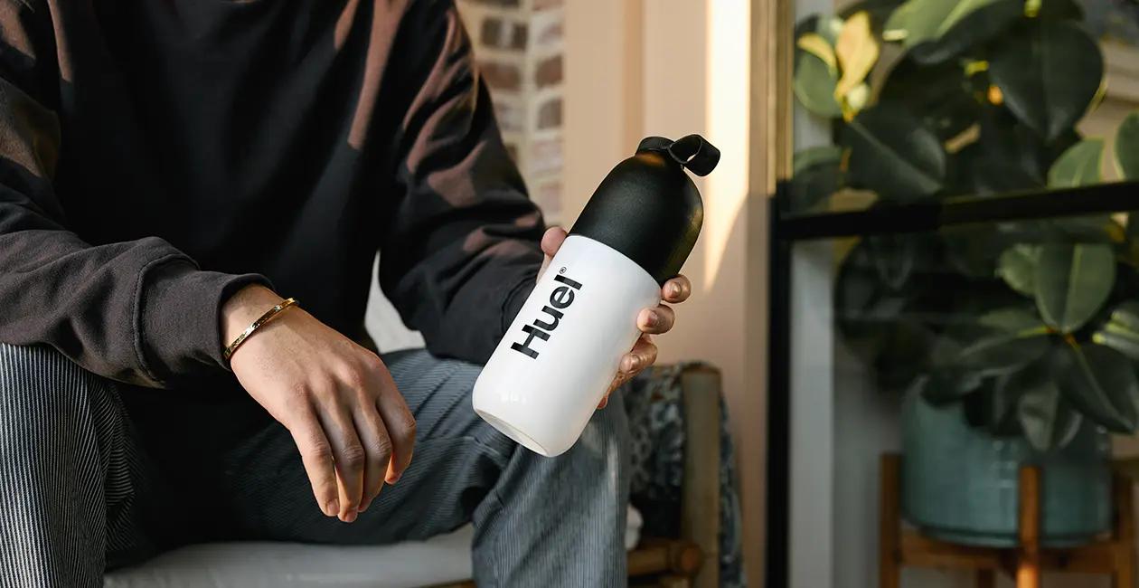 man sat on a chair holding a Huel shaker