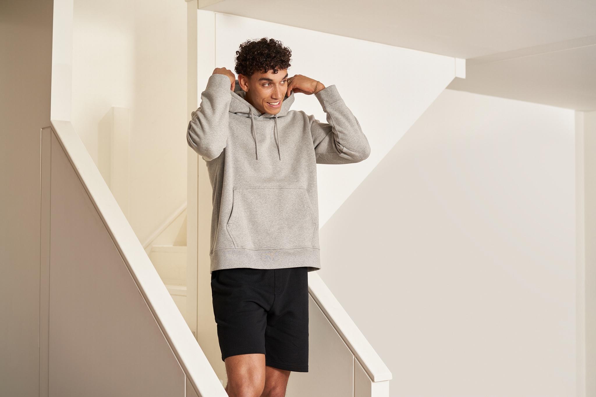 man walking down stairs adjusting the hood of his hoodie