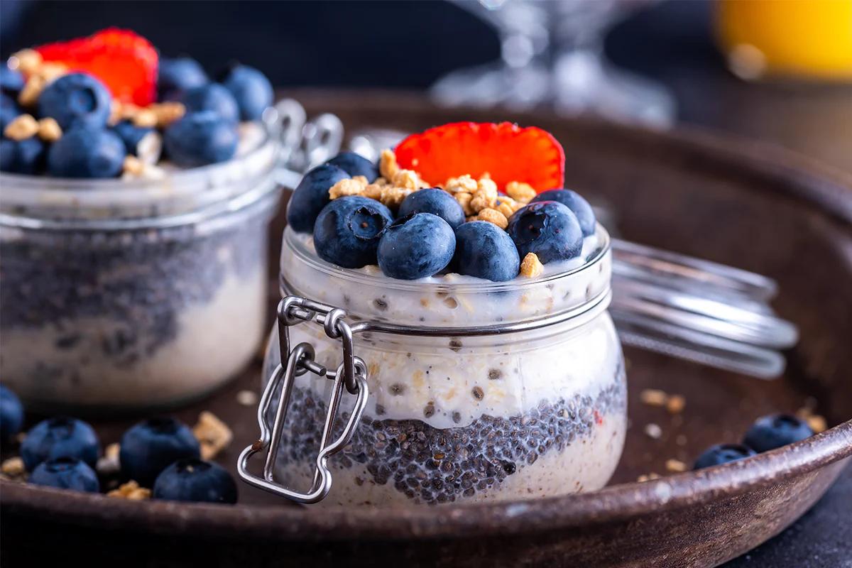 two jars filled with oats seeds blueberries strawberries and more making for a nutritious breakfast