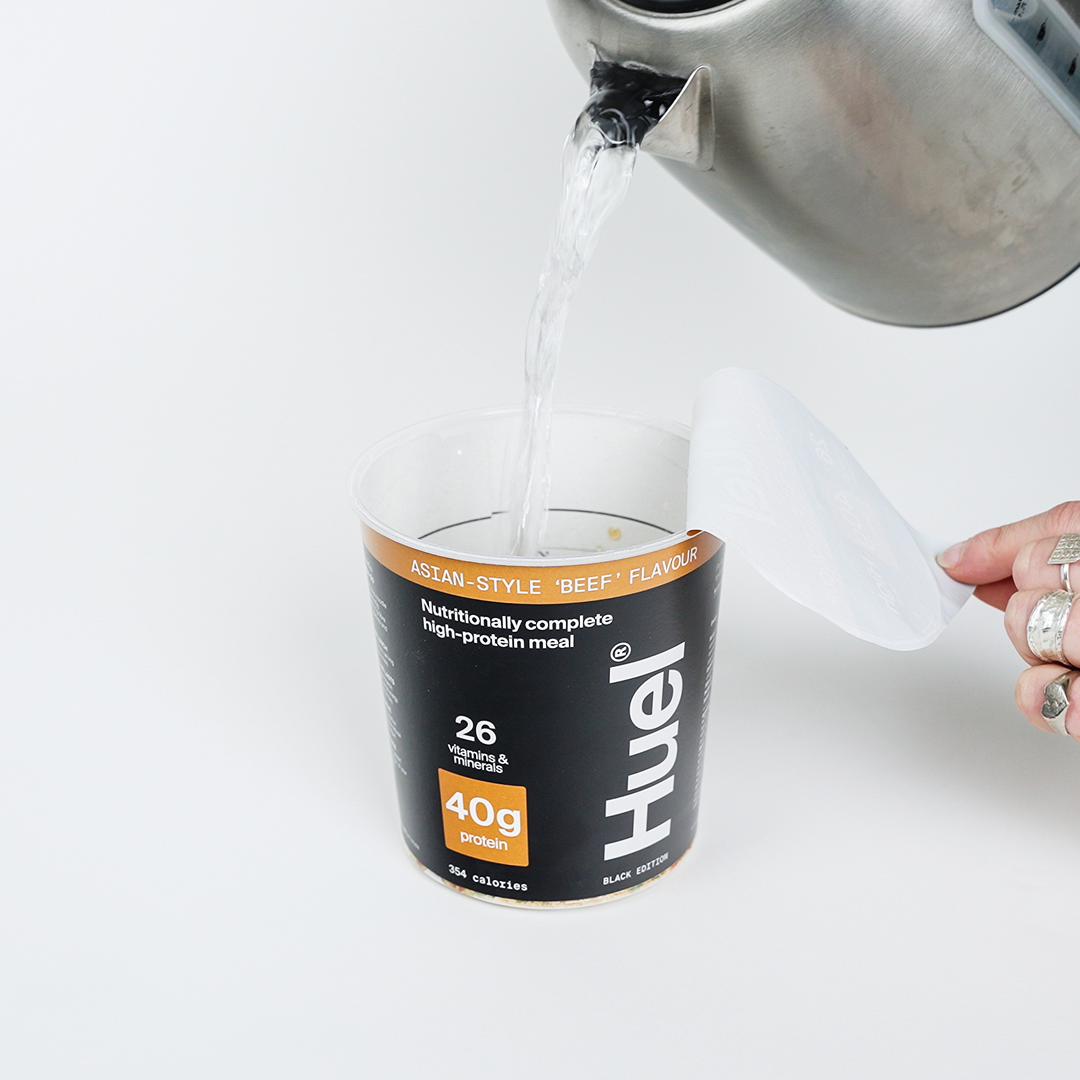 A Huel Black Edition Ramen pot with water being poured into it