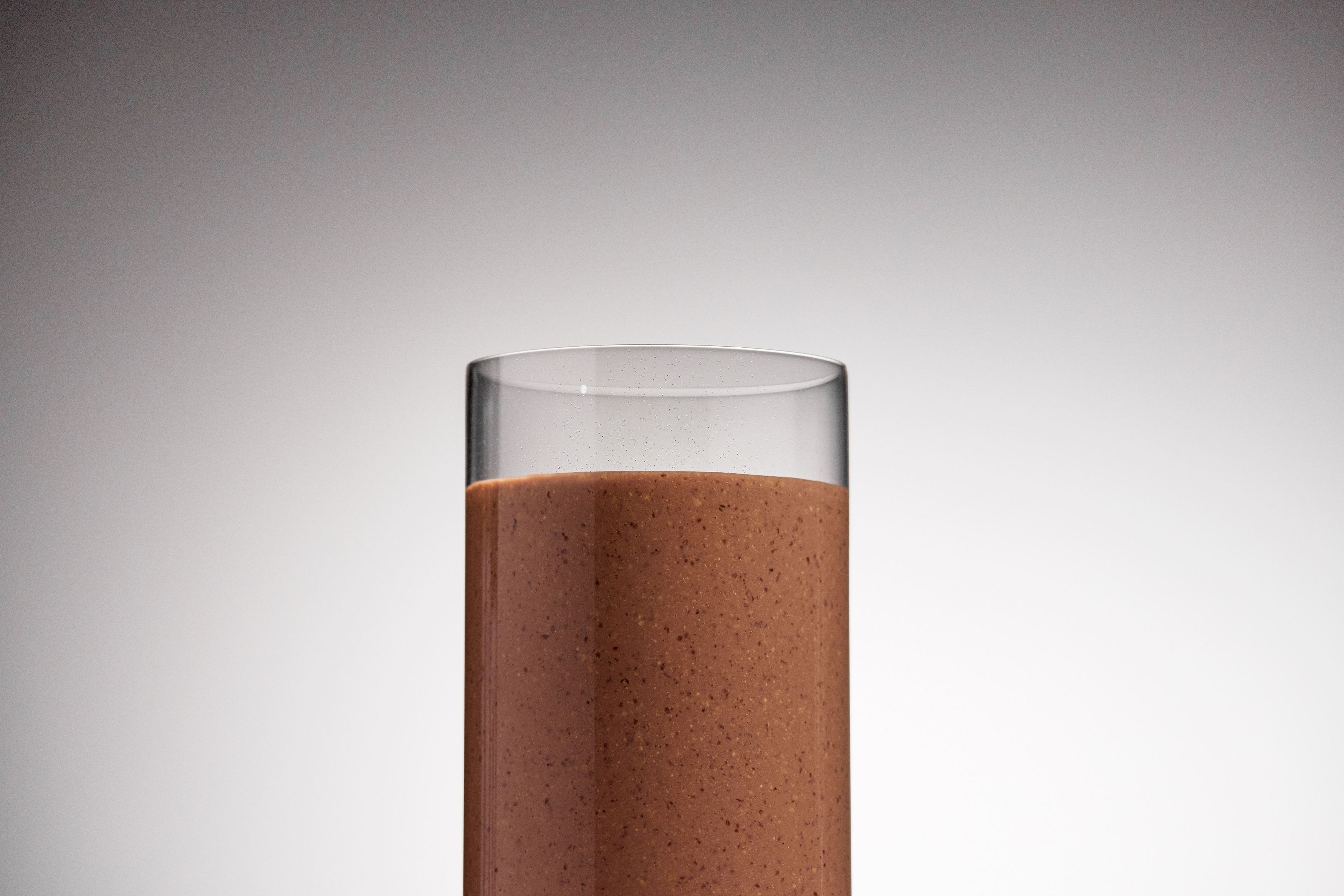 Image of a glass of chocolate Huel set against a grey / white background