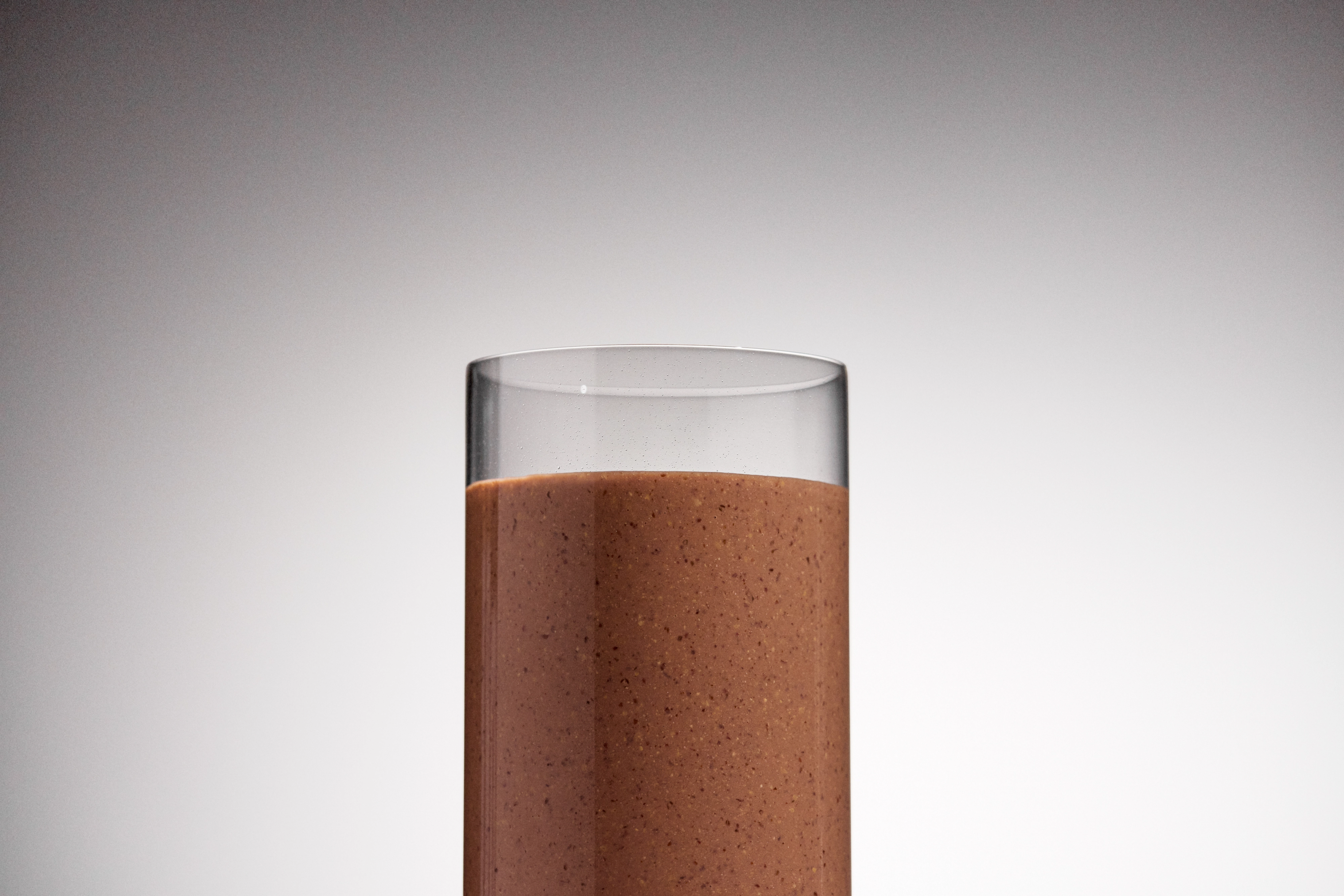 Image of a glass of chocolate Huel set against a grey / white background