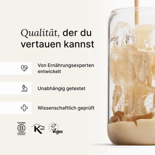Huel vanilla shake being poured into a glass with ice, against a neutral background