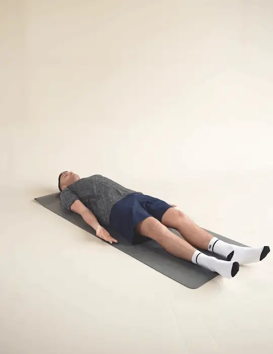 Man performing a supine decompressions stretch whilst laying on a yoga mat