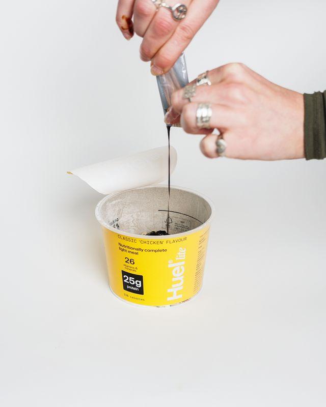 Someone pouring a sachet of sauce into the Huel Lite Ramen pot