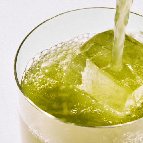 A close up of a glass of Daily Greens Ready-to-drink in a glass with ice