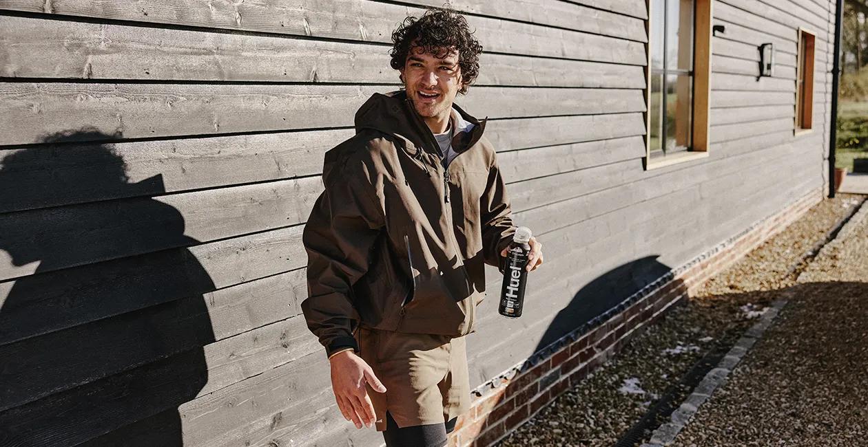man stood outside smiling holding a Huel Black Edition Ready-to-drink