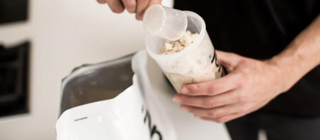 Huel Original being scooped into a Huel shaker