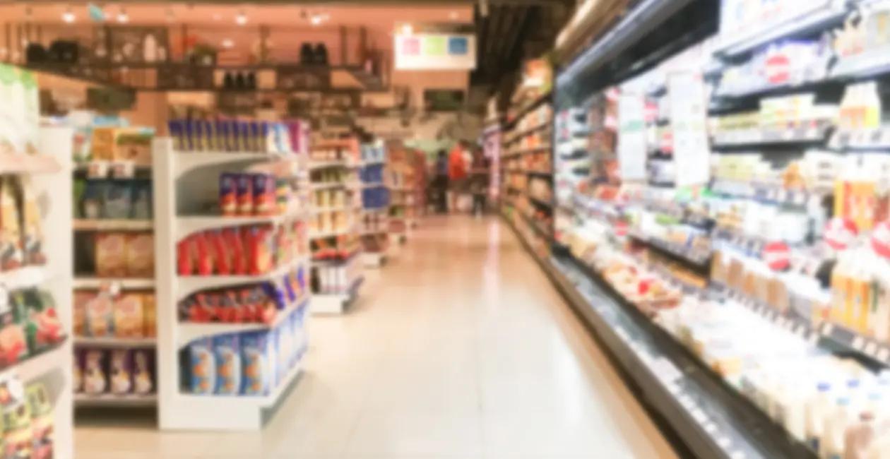 inside a supermarket shelves along the left hand side with refrigerated section along the right