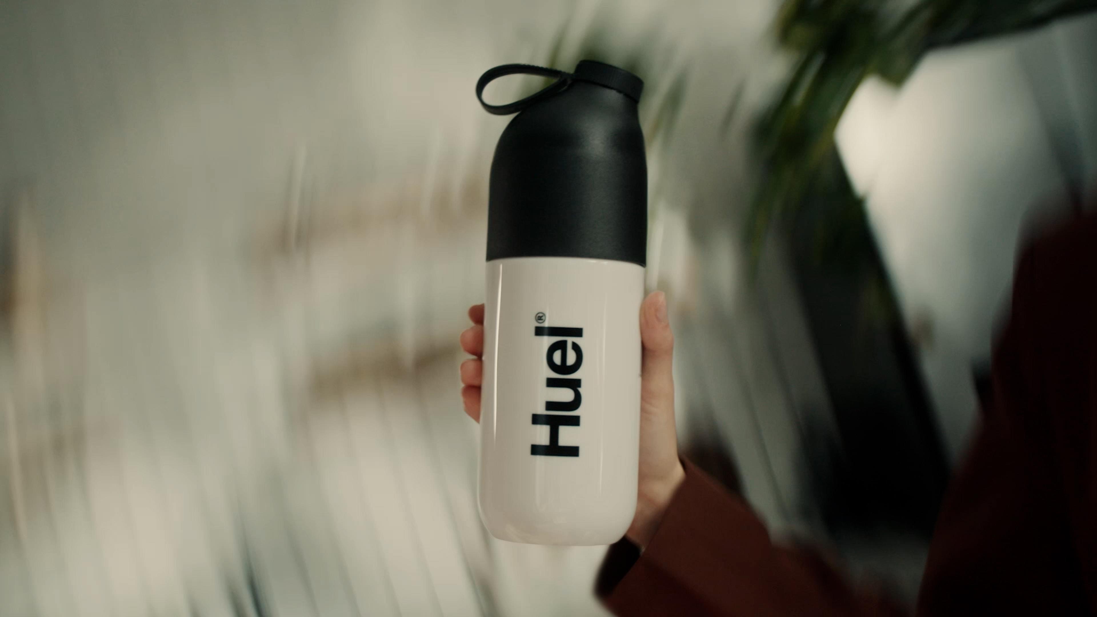 An image of Huel being shaken in an original black and white Huel shaker with a blurry background 