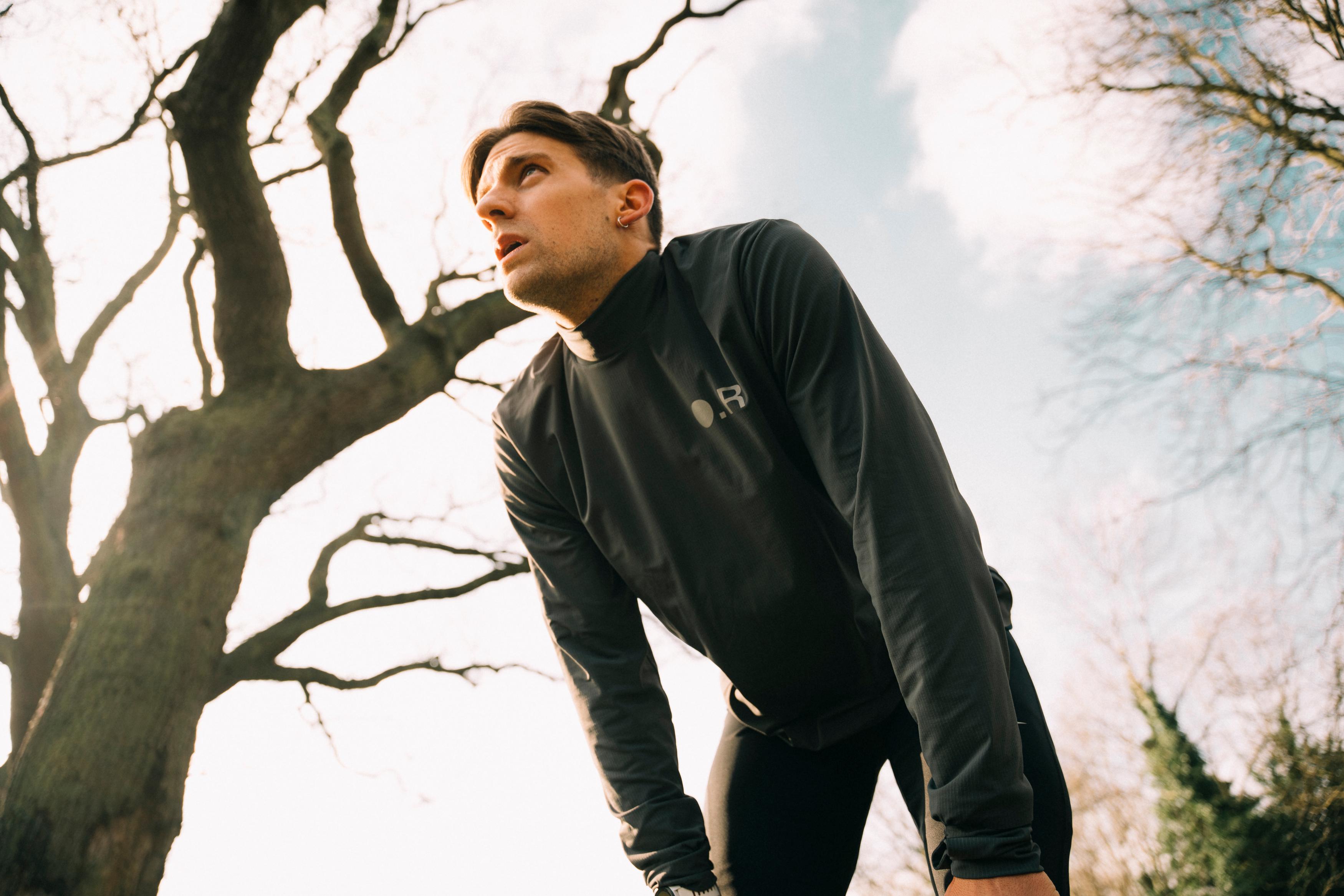 man outside bent over with his hands on his knees catching his breath