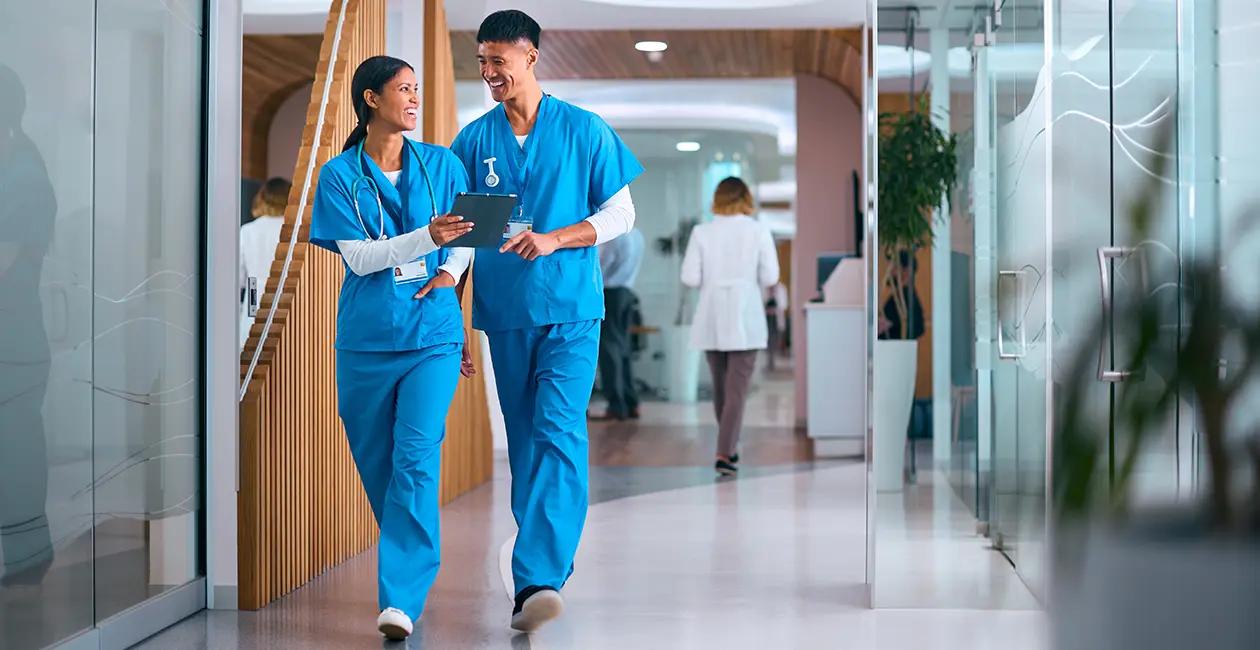 doctors walking down a hallway holding a clipboard and smiling