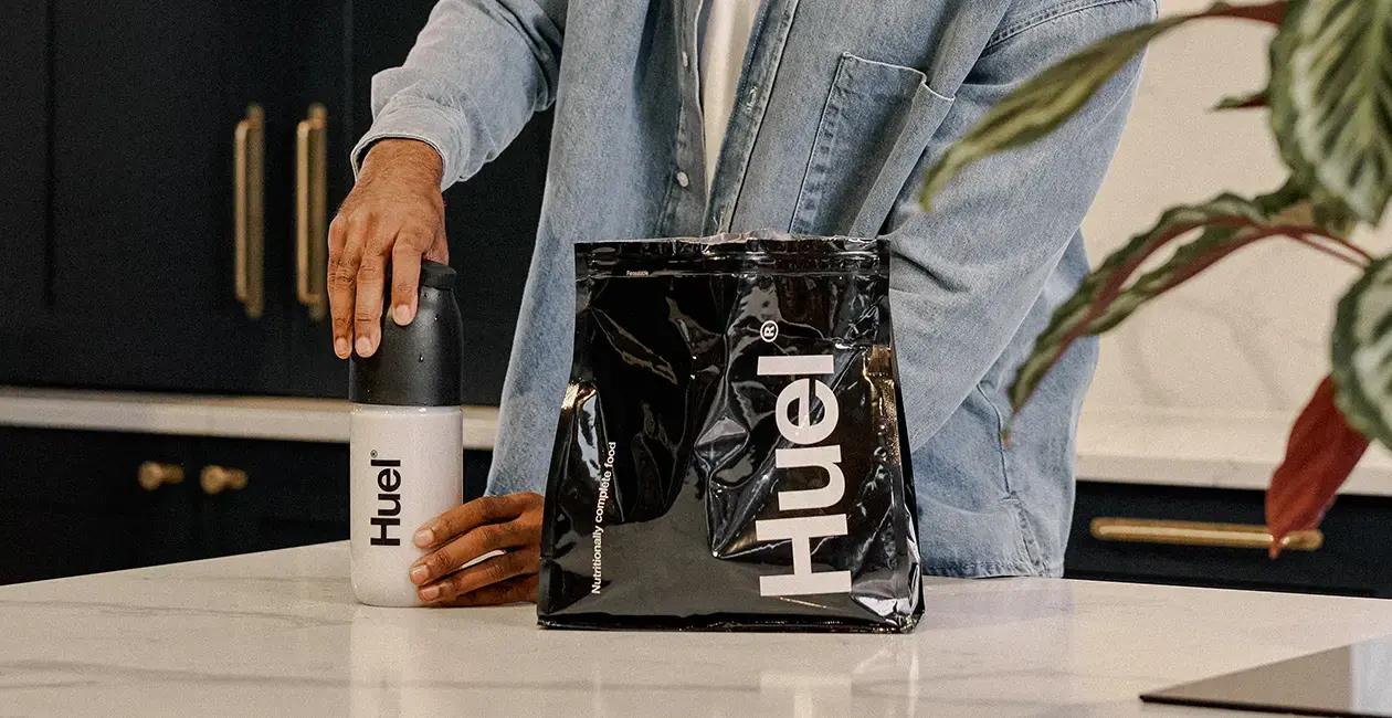 person making Huel Black Edition meal shake in a Huel shaker on a kitchen counter