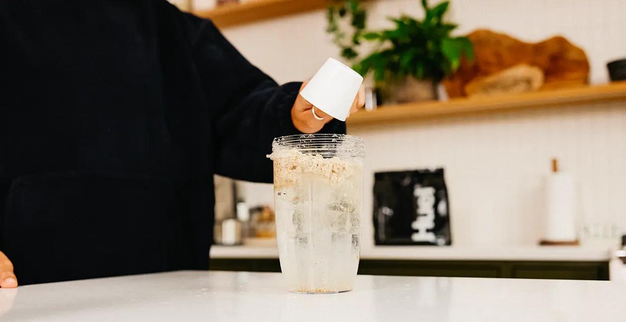 someone adding Huel Powder to water in a blender