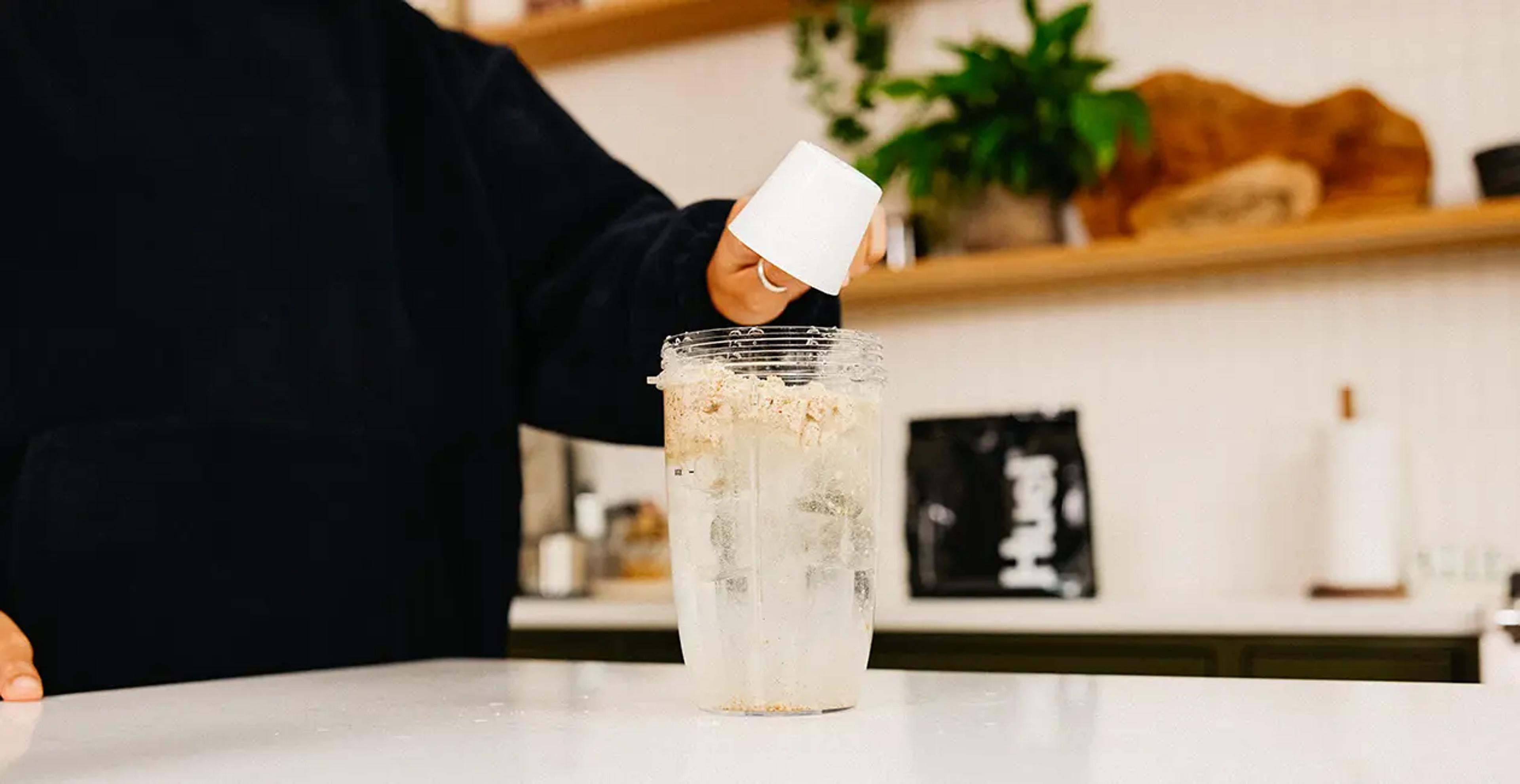 someone adding Huel Powder to water in a blender
