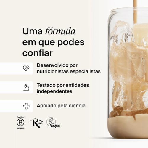 Huel batido de baunilha a ser vertido num copo com gelo, contra um fundo neutro