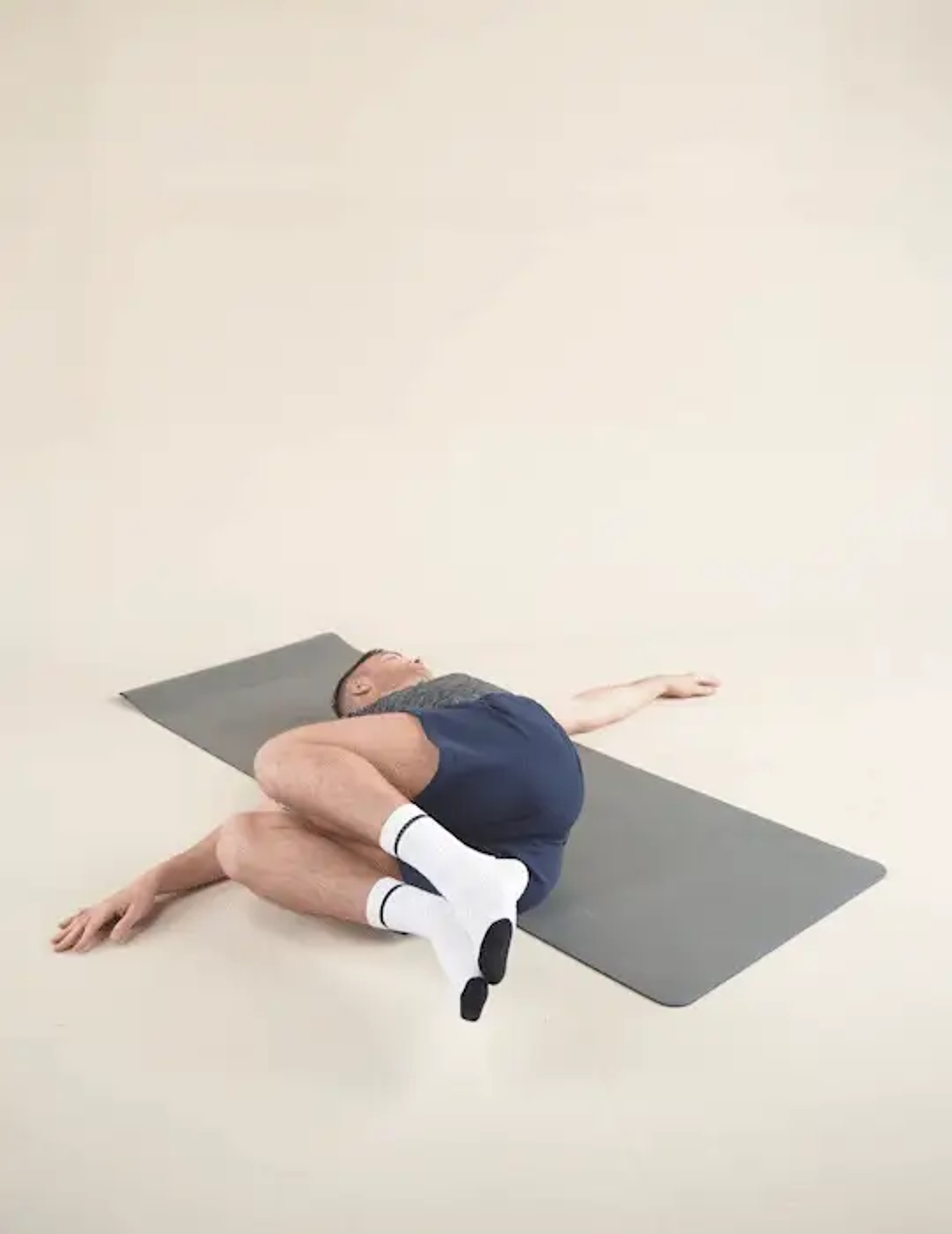 GIF of a man doing a Trunk Rotation stretch while laying on a yoga mat
