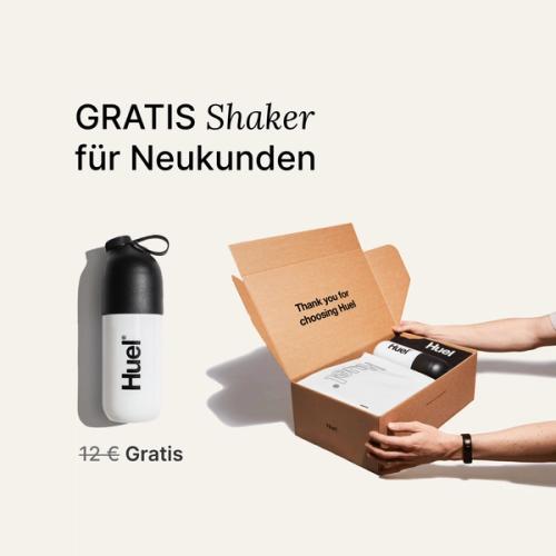 someone holding a Huel box containing a white powder bag, and a black and white shaker, on a neutral background