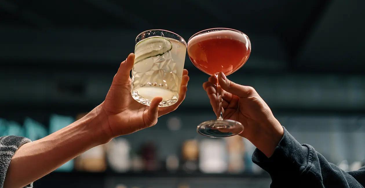 two cocktails being held up next to one another