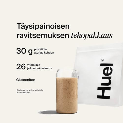 A bag of Huel powder next to a glass containing a Huel drink on a neutral background