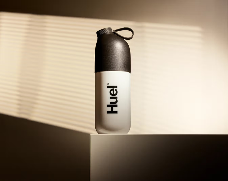 A Huel shaker on a stand with lighting around it to make it stand out