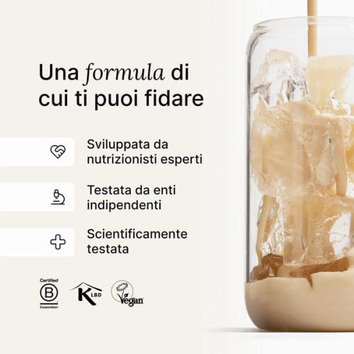 Huel vanilla shake being poured into a glass with ice, against a neutral background