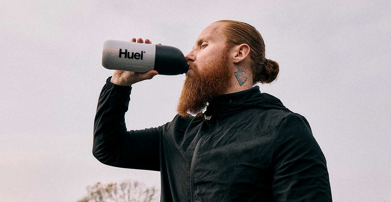 Russ Cook drinking from a Huel shaker outside