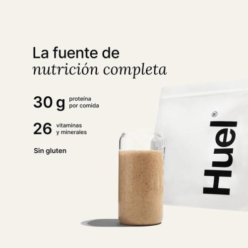 Una bolsa de Huel Powder junto a un vaso que contiene una bebida de Huel sobre un fondo neutro