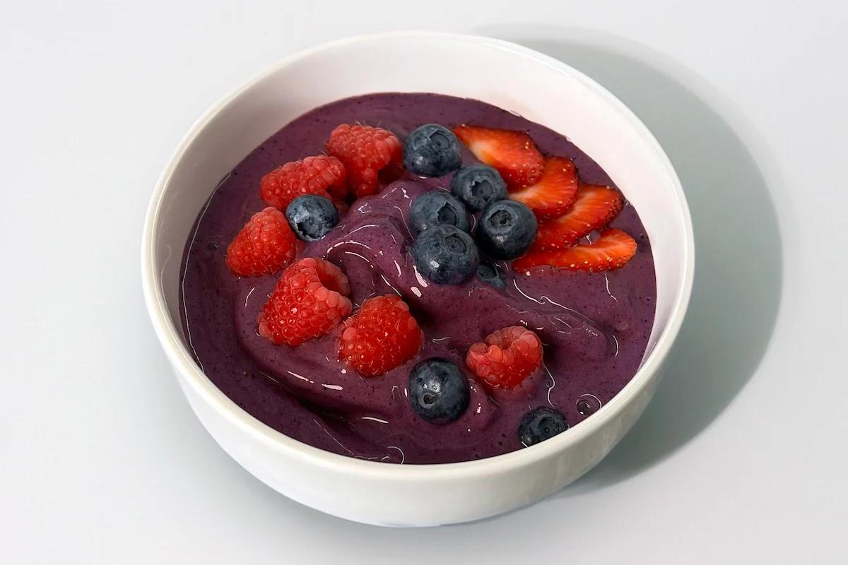 Purple smoothie bowl with raspberries, blueberries, and strawberries on top