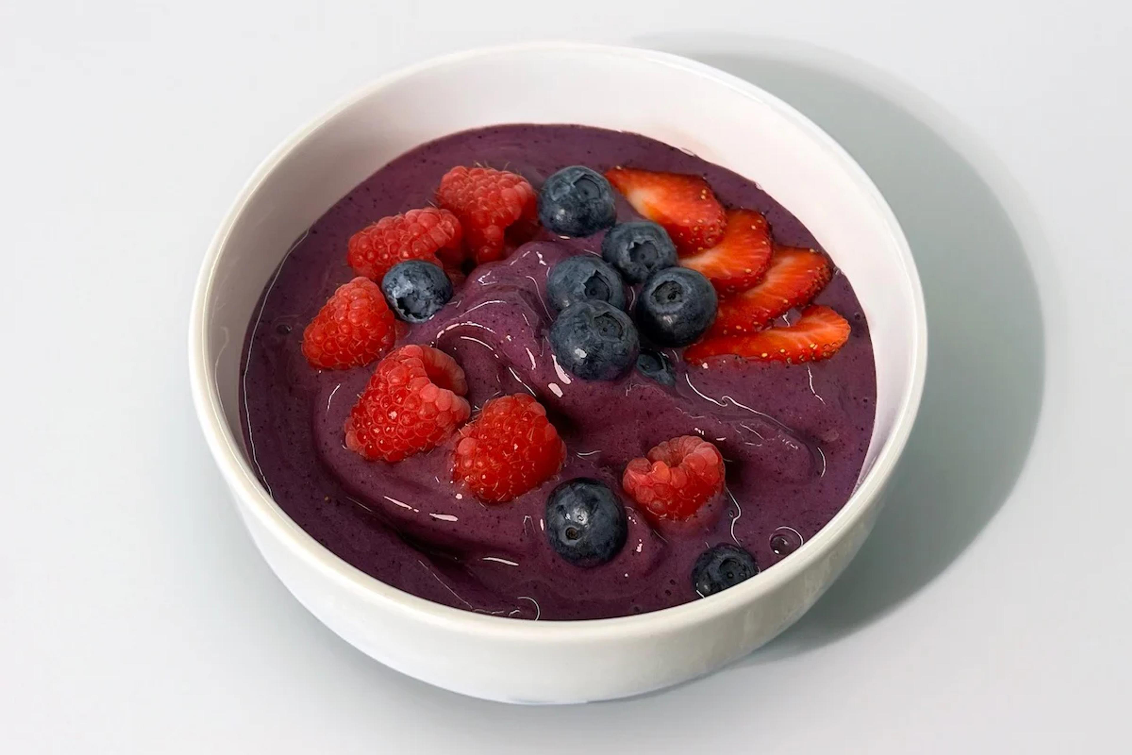 Purple smoothie bowl with raspberries, blueberries, and strawberries on top