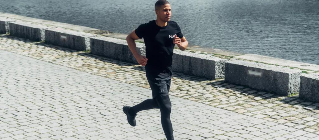 A man running in a Huel t-shirt next to a body of water