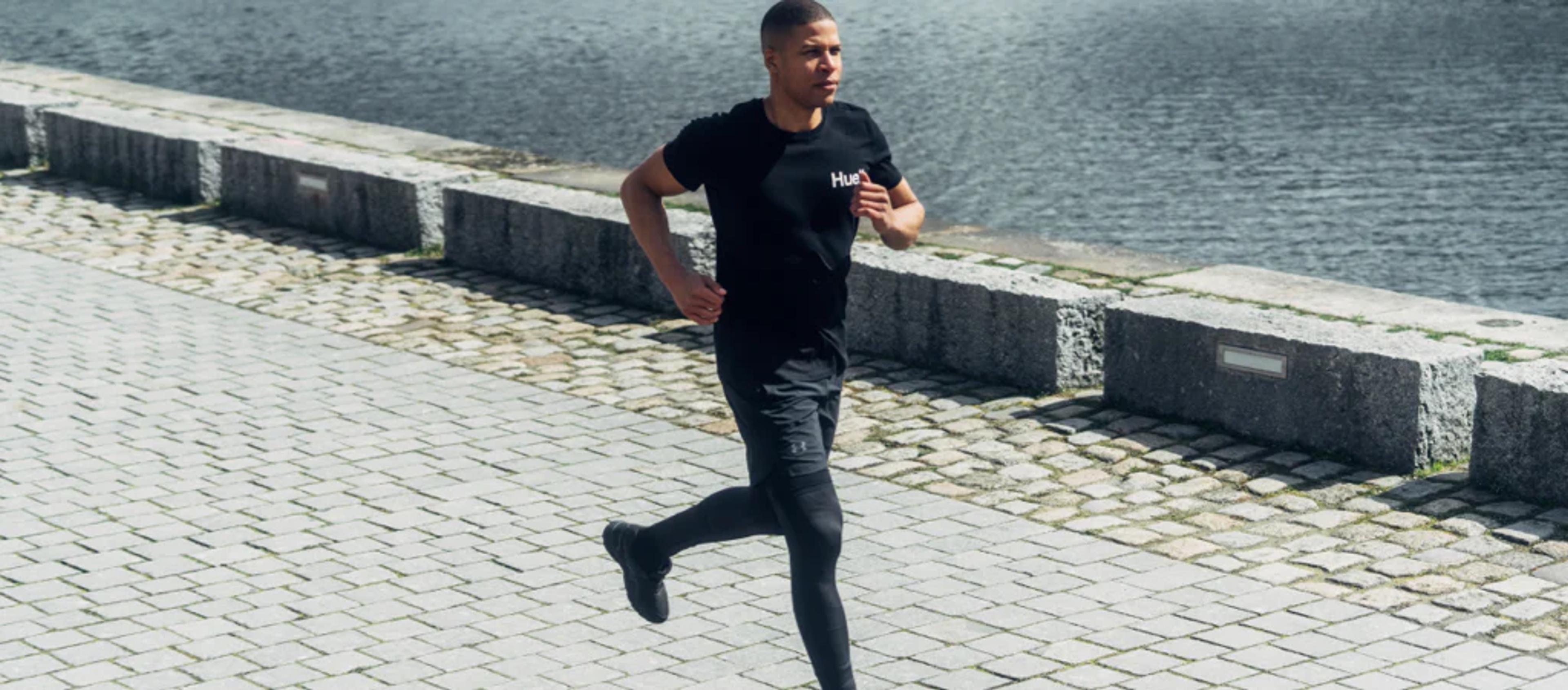 A man running in a Huel t-shirt next to a body of water
