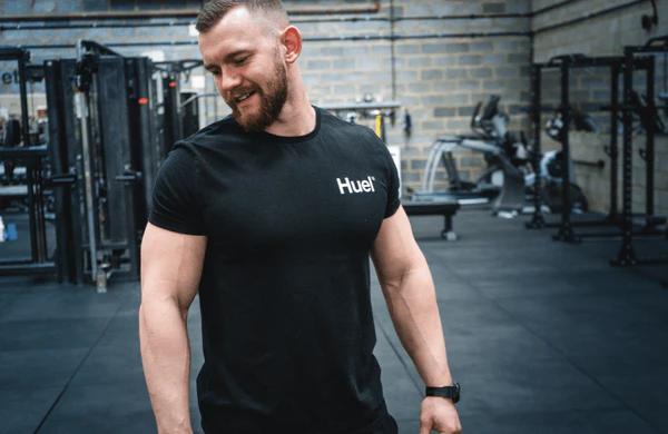 man in gym wearing a Huel tshirt looking down at the ground