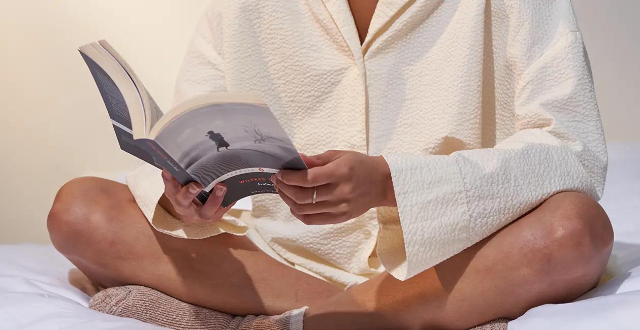 woman sat on bed reading a book