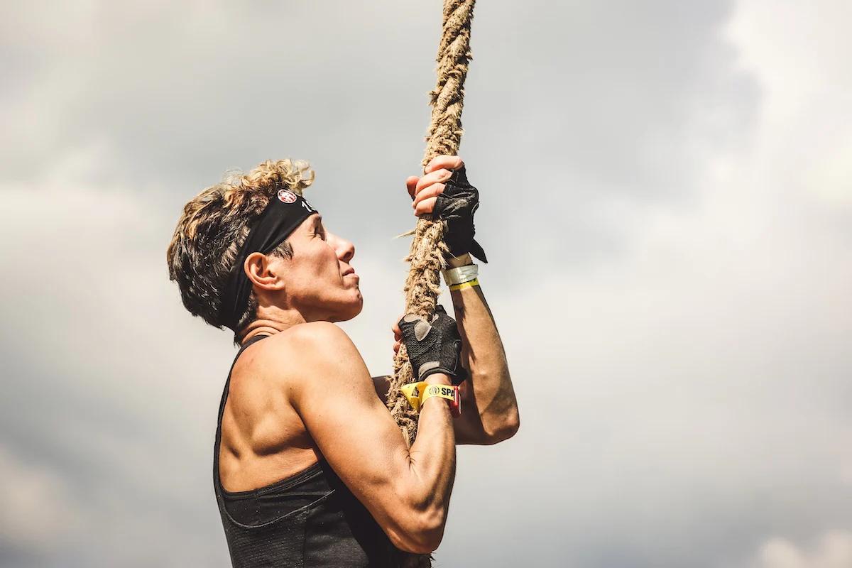 man climing a rope outside wearing gloves and a headband