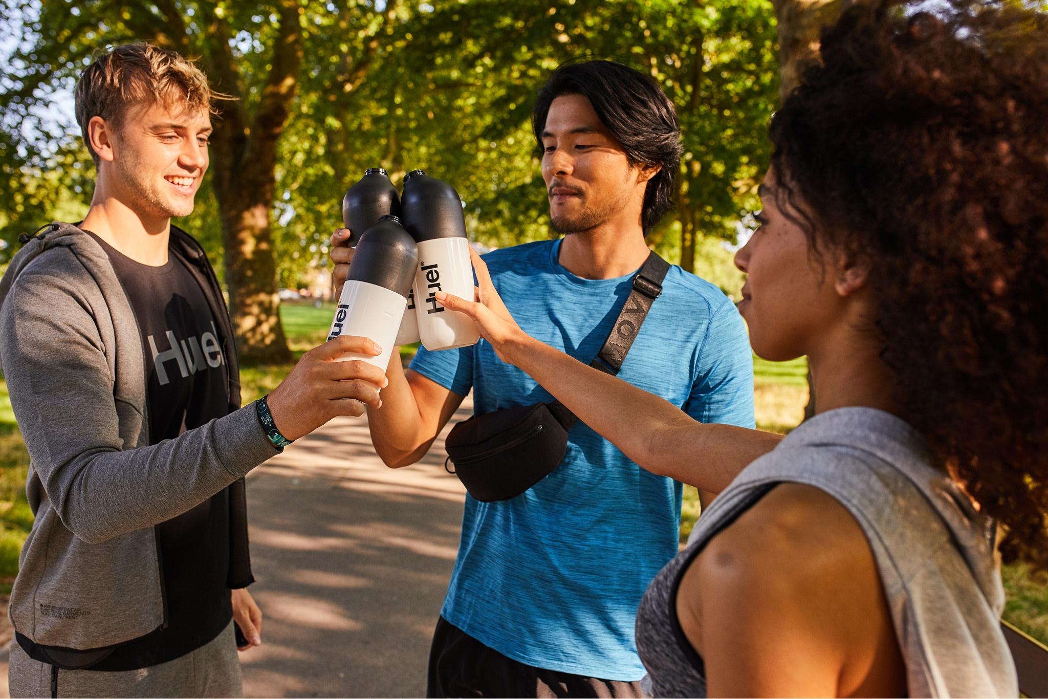 three people outside cheersing their Huel shakers
