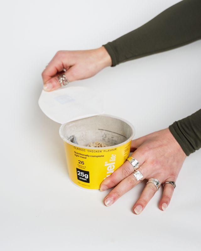 A Huel Lite Ramen in classic 'Chicken' flavour with a person opening the lid
