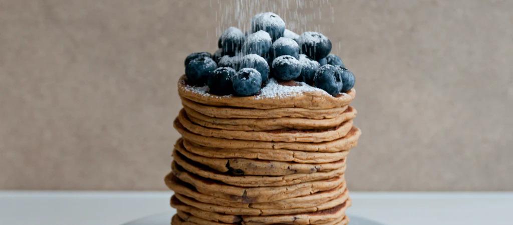 A stack of Huel Pancakes with Blueberries on top and powdered sugar
