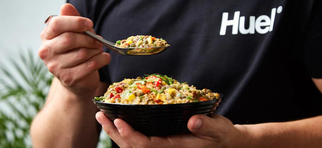 Man in Huel t-shirt eating Huel hot and savoury from a bowl