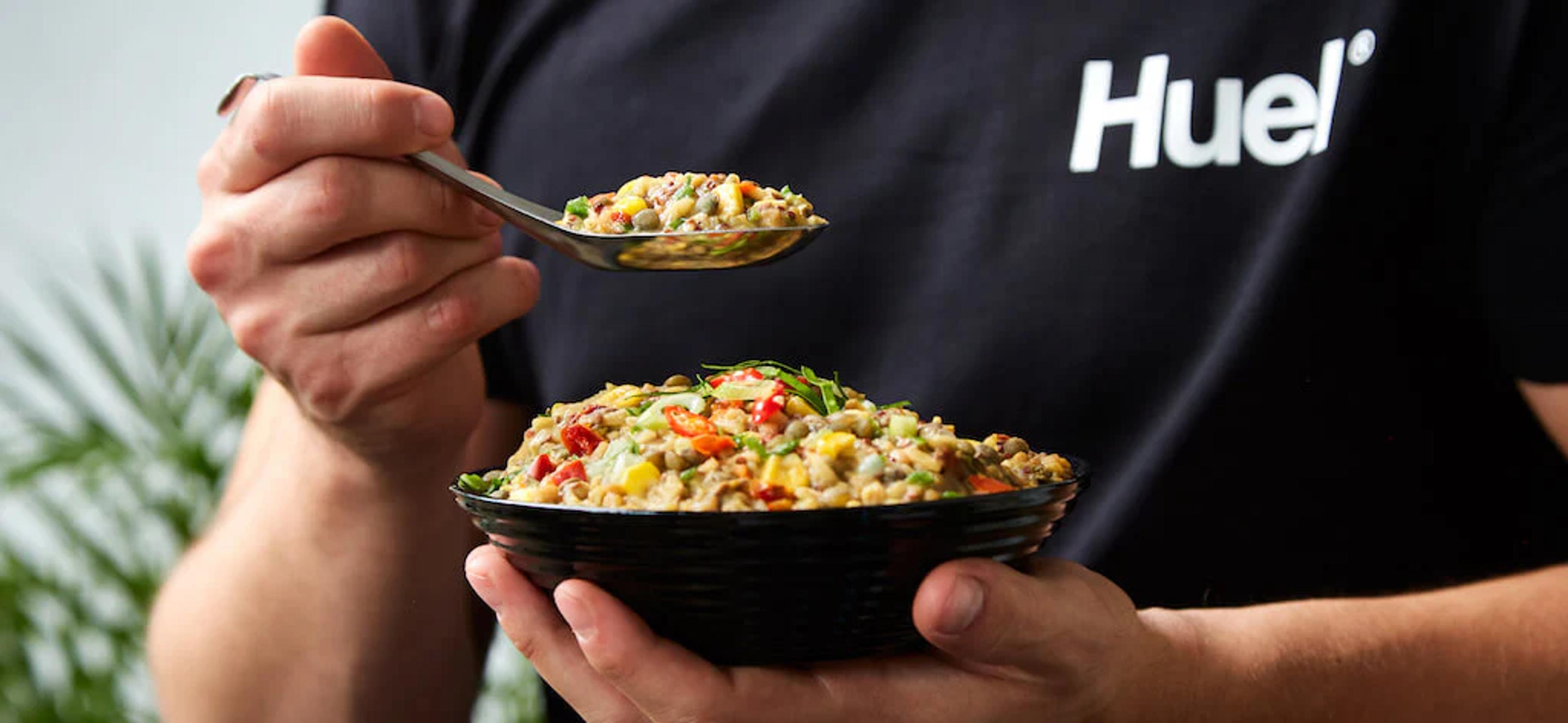 Man in Huel t-shirt eating Huel hot and savoury from a bowl