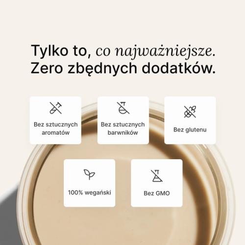 Szklanka pełna koktajlu białkowego Huel na neutralnym tle.
